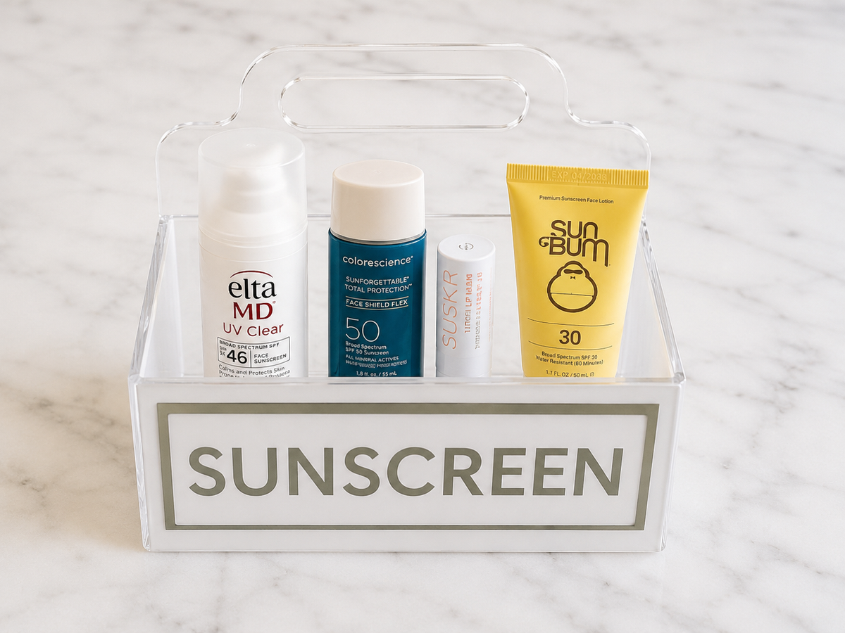 Personalized lucite caddy styled poolside, holding sunscreen and beach essentials.